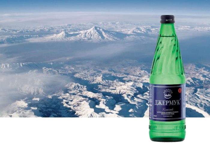 бутылка с минеральной водой на фоне заснеженных холмов