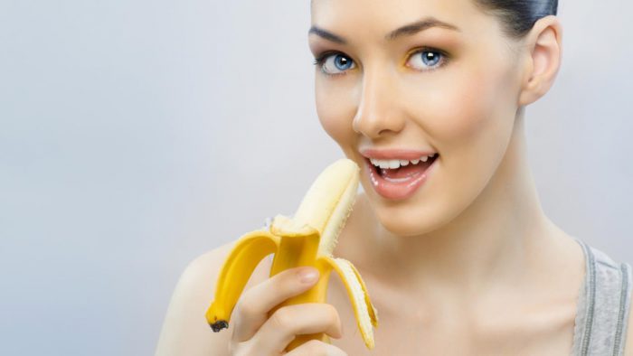 Девушка ест банан