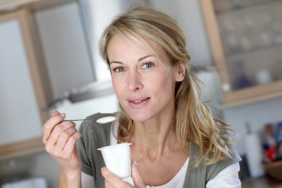 Женщина ест йогурт