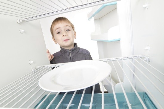 Мальчик заглядывает в пустой холодильник