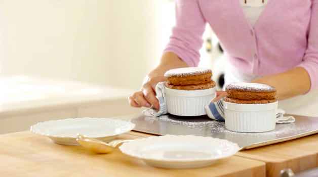 Placing fully baked chocolate souffles dusted with powdered sugar on a serving plate
