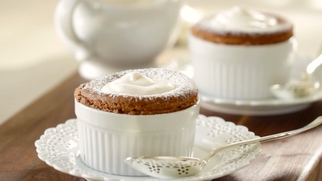 Two Chocolate Souffles on a table topped with whipped cream