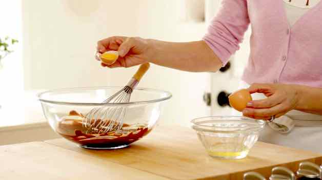 Adding egg yolks to a chocolate base in a glass bowl