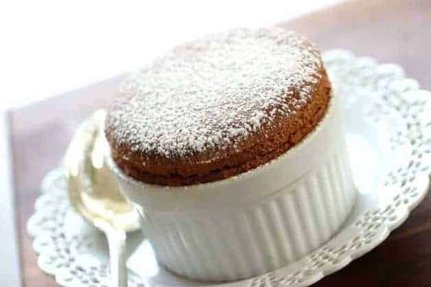 Chocolate Souffle in ramekin sitting on a white plate with silver spoon 