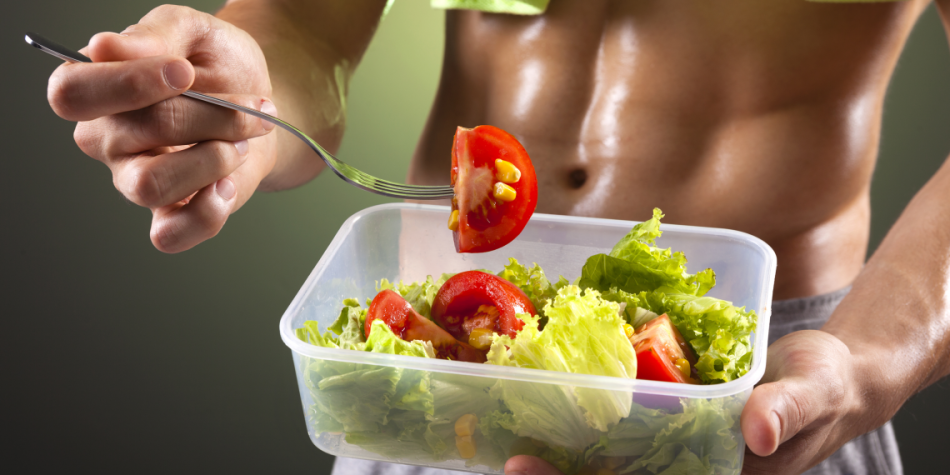 Мужчина кушает овощной салат после тренировки