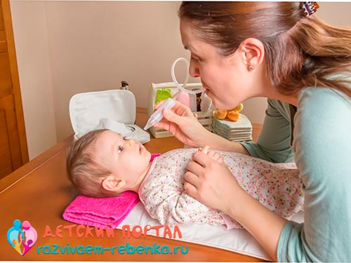 Мама чистит нос новорожденного аспиратором