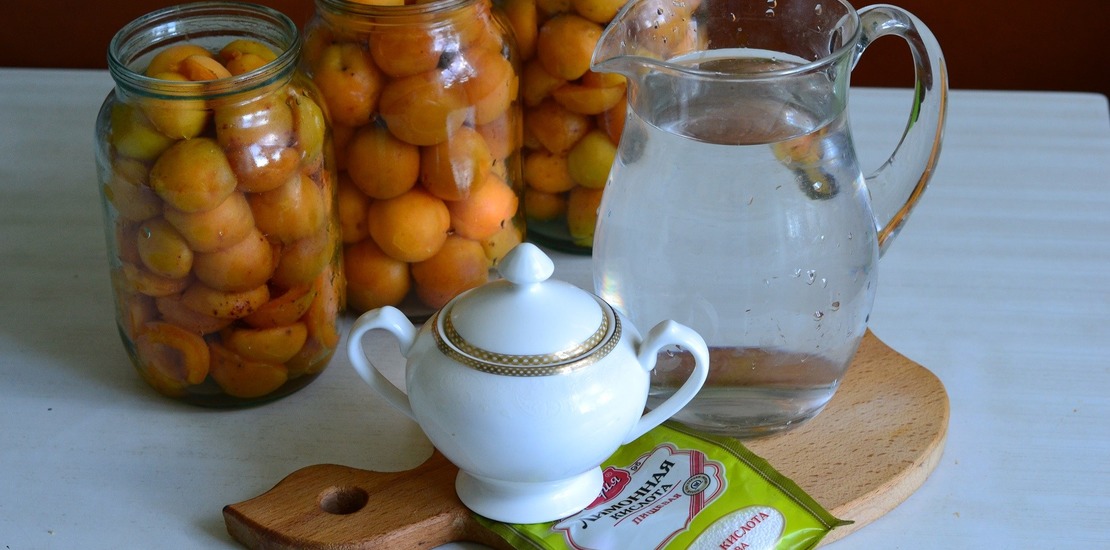 литровые банки с абрикосами, вода в кувшине, сахар в сахарнице и лимонная кислота в пакетике
